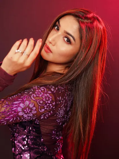 A close-up portrait of actress Donal Bisht, using dramatic red lighting to create a bold and intense mood that complements her sequined outfit.