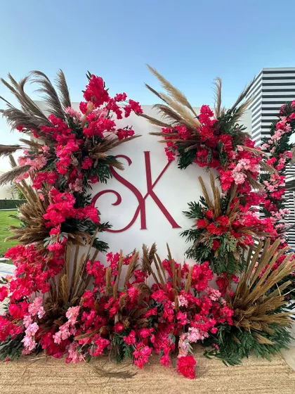 A sunny day in Doha calls for a beautiful photo-op. The couple's monogram is framed by a wreath of red flowers and pampas grass, creating a modern and chic look. 🌺