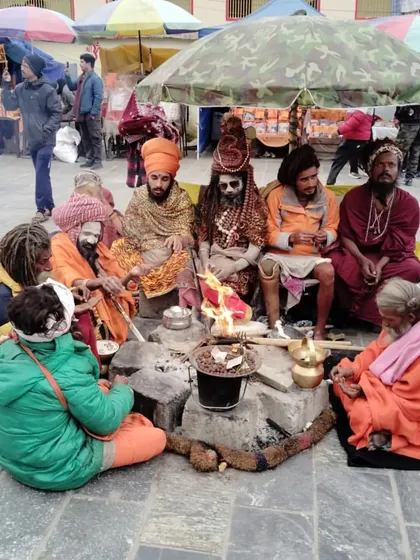 **Sadhus at Kedarnath.** A group of sadhus sitting around a sacred fire in the temple courtyard, their presence adding to the spiritual aura of the place.