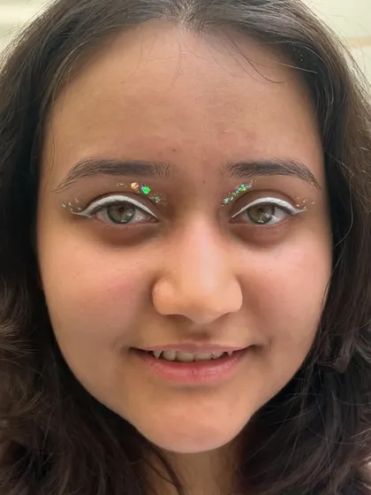 A creative look using a white graphic liner and green glitter on the inner corners. It's a simple but effective way to create a unique and eye-catching makeup style.