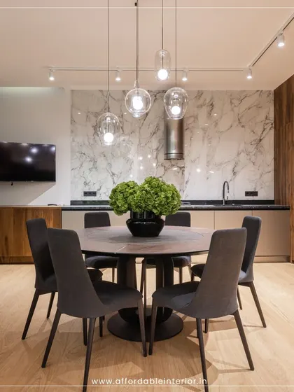 A modern dining space where a round table encourages conversation. The design is elevated by a marble accent wall, wood-paneled cabinets, and statement pendant lighting.