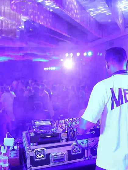 A view from behind the console, looking out at a packed corporate party. The custom 'Mervin' shirt is part of my professional branding for events.