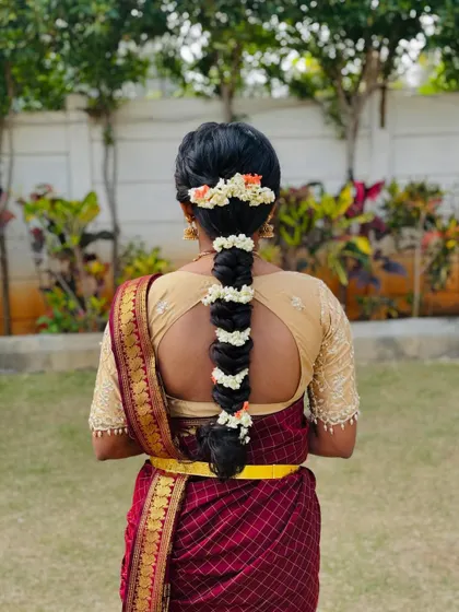 A traditional bubble braid hairstyle, with sections wrapped and decorated with fresh jasmine and orange flowers.