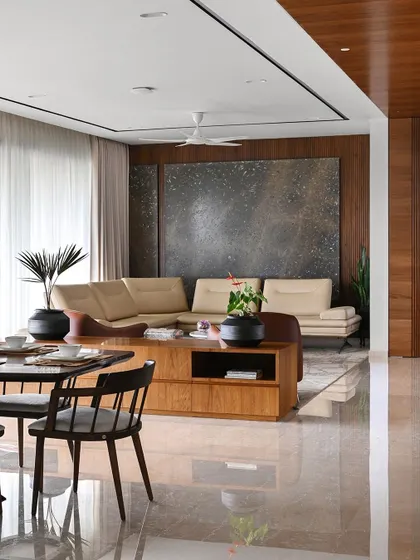 A large, abstract art piece complements the sectional sofa, adding texture and a focal point to the living space. The entire area is unified by polished marble flooring.