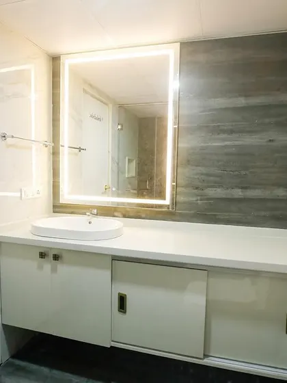 The modern bathroom in Richa and Abhay's home, featuring a backlit mirror and a sleek white vanity. The design is clean, bright, and highly functional.