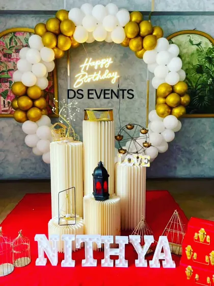 A classic and clean white and gold theme. This decoration includes a circular balloon arch, a "Happy Birthday" neon sign, and marquee letters spelling out the name, all set against a vibrant red carpet for a touch of drama.