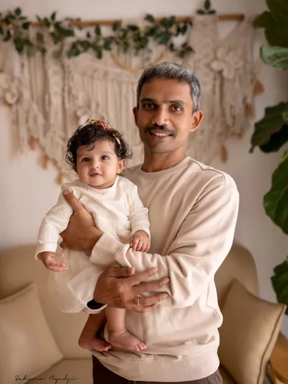 A grandfather holds his baby granddaughter. The gentle way he holds her and her curious expression make for a heartwarming multi-generational portrait.