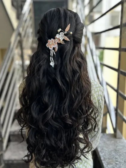 A beautiful half-up, half-down style with soft waves, adorned with a delicate, modern floral hairpiece.