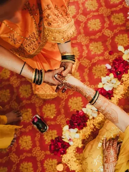 An overhead shot of a Haldi ritual, focusing on the hands and the traditional elements.
