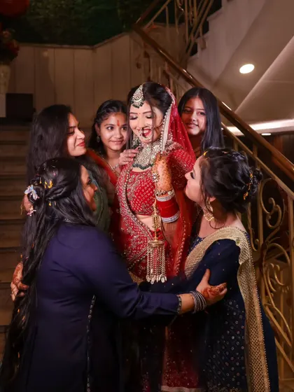The bride surrounded by her closest friends, who are helping her with her kaleeras. A moment of friendship and support.