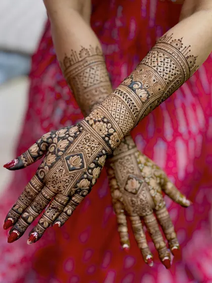 A crossed-hands view of the freshly applied mehendi, highlighting the complexity of the design.