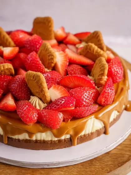 A strawberry and Biscoff cheesecake. This image focuses on the contrast of fresh fruit and caramel drizzle, creating a visually appealing and delicious-looking dessert.
