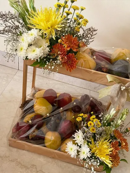 Wedding gifts made bright and colorful with our floral fruit platters. This two-tiered stand holds fresh fruit, beautifully wrapped and adorned with arrangements of yellow and orange chrysanthemums.