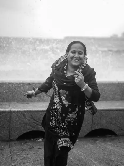 A black and white photo series capturing the spirit of Mumbai's monsoon at Marine Drive. People are seen enjoying the high tide, getting drenched by waves, and finding joy in the downpour.