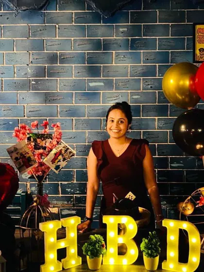 The birthday girl smiling brightly at her surprise celebration. The warm glow of the marquee letters and the personal touches create a wonderful atmosphere for capturing happy memories.