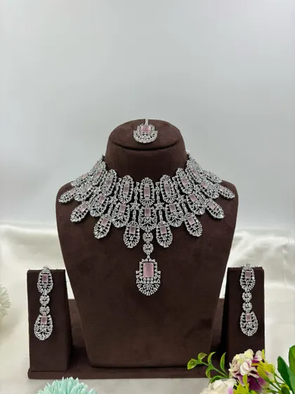 A full-coverage AD bridal set with a matching maang tikka. This silver-plated design is available in a wide range of colors like green, blue, pink, and white, making it a versatile choice for weddings.