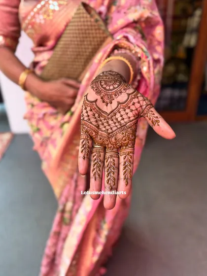 A close-up of a beautifully executed guest mehendi, showing the clean lines of the grid pattern and leafy finger details.
