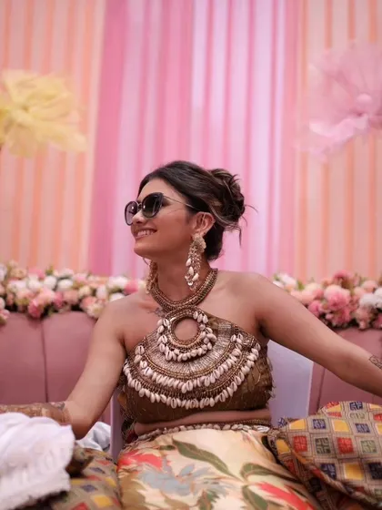 A client enjoying her nature-inspired Mehendi. Her long, shell-detailed earrings were custom-made to complement her unique halter-neck blouse and bohemian theme.