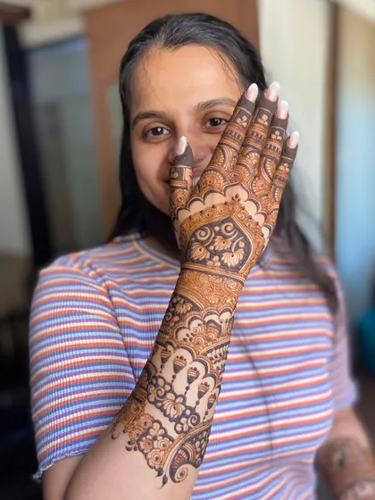 The same happy client, her joy evident as she displays her beautiful henna.