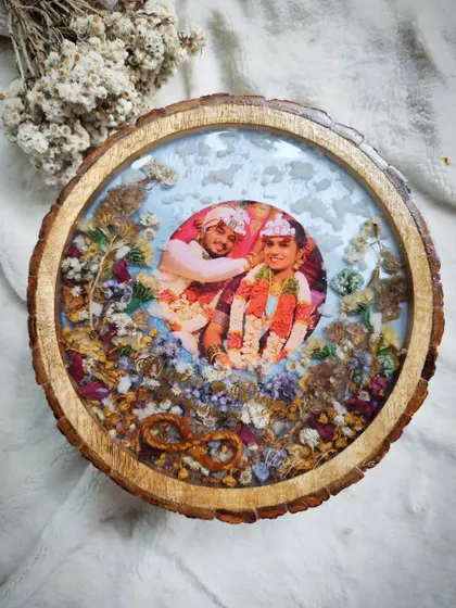 For a more rustic and natural feel, I create keepsakes on beautiful wooden logs. This dreamy frame for my client Divya uses her varmala flowers to create a snow-like effect, highlighting a memory from a special trip and bringing a piece of nature indoors.