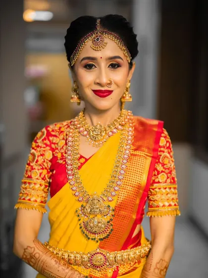 A classic bridal portrait. The bride's yellow and red Kanjeevaram is perfectly complemented by her gold temple jewelry.
