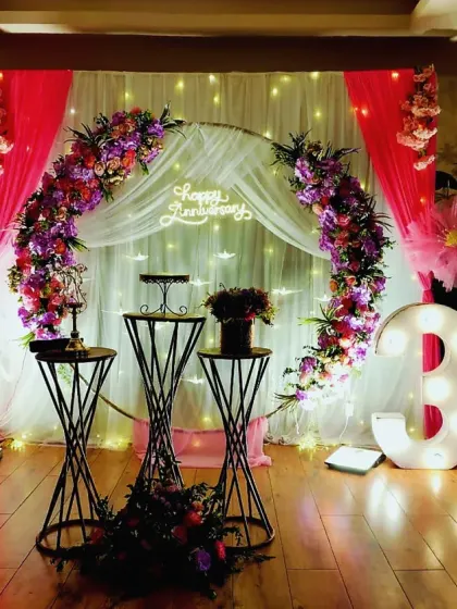 Celebrating 35 years of love with a sophisticated and romantic floral setup. We used a circular arch adorned with purple and pink flowers, sheer drapes with fairy lights, and illuminated numbers to create a magical ambiance for this special anniversary.