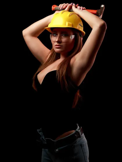 A powerful and playful pose from the construction-themed shoot. The model holds a hammer, adding to the strong and unconventional character.