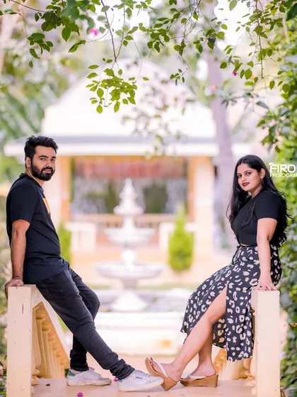 A cool, symmetrical pose on a railing with a fountain in the background. This modern portrait in casual wear has a stylish and relaxed vibe.