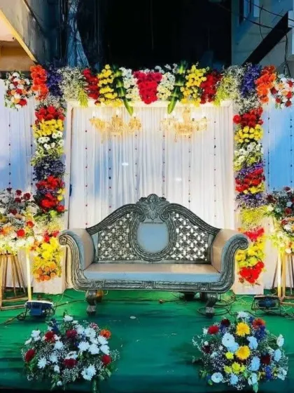 A vibrant and colorful engagement stage with a multi-colored floral arch and bright green flooring.