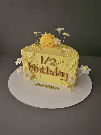 Rise and shine! A sunshine-themed half-birthday cake for Jordan. This chocolate praline cake is decorated with a cute sun and daisies.
