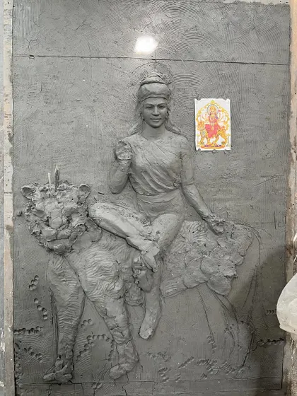 Another angle of the initial clay work for the Maa Durga sculpture, with a reference picture pinned to the board to ensure accuracy and devotion in every detail.