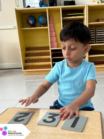 A child learns number recognition with sandpaper numbers. Touching the shape of the number creates a multi-sensory connection that makes learning effortless.