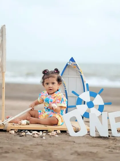 The birthday girl sits proudly on her mini-boat prop, ready to set sail on her first birthday adventure.