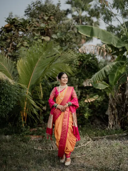 A stunning portrait of the bride surrounded by palm and banana trees, her colorful saree vibrant against the green backdrop.