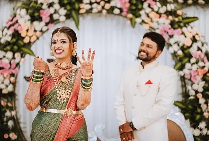 A candid moment of a happy bride at her engagement, with a circular floral arch creating a perfect frame.