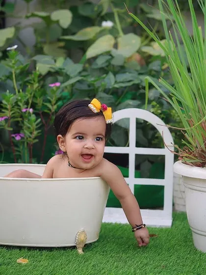 Looking so sweet and curious during her outdoor splash session, surrounded by lush green plants.