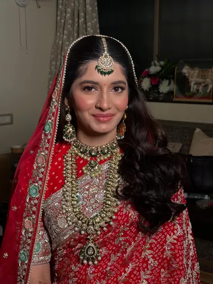 A regal half-updo with soft curls, adorned with beautiful, traditional hair accessories. This hairstyle is perfect for a bride who wants a royal look for her wedding day.