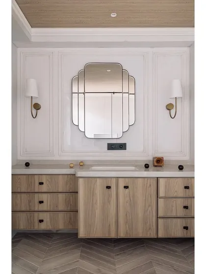 A full view of the den's vanity area, featuring an elegant art-deco-inspired mirror and custom wood cabinetry. The design combines classic motifs with modern simplicity.