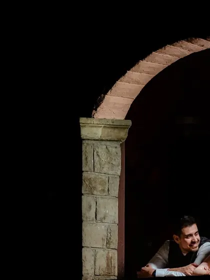 An artistic portrait using shadows and architecture. The couple is framed within an archway, creating a sense of intimacy and mystery.