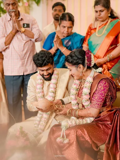 A candid moment of laughter between the couple during a wedding ritual, with family looking on.