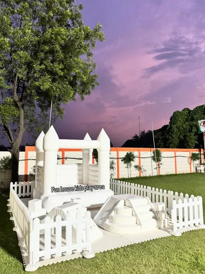 Our white play area set against a dramatic twilight sky. This setup includes a bouncy castle, a covered climber, and steps, creating an inviting play space.