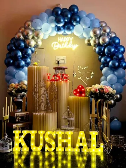 An elegant birthday setup for Kushal with a blue and silver balloon arch. The arrangement of props and marquee letters creates a sophisticated look.