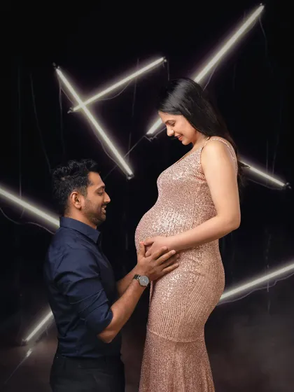 An intimate moment between a couple, framed by the contemporary glow of neon lights for a unique maternity photo.
