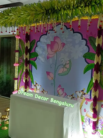 This artificial flower setup features a beautiful lotus-themed Pichwai backdrop. It's a great example of how we can achieve a traditional look that is both stunning and budget-friendly.