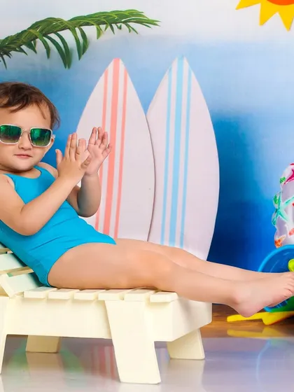 This little girl is channeling her inner cool, lounging on a beach chair with sunglasses. A fun and sassy pose that shows off her personality.