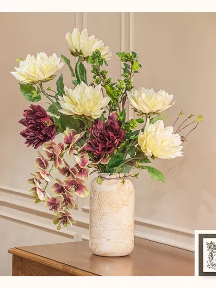 The art of arrangement can turn ordinary elements into an extraordinary bouquet. This mix of cream and burgundy dahlias in a textured vase creates a stunning display for a side table.