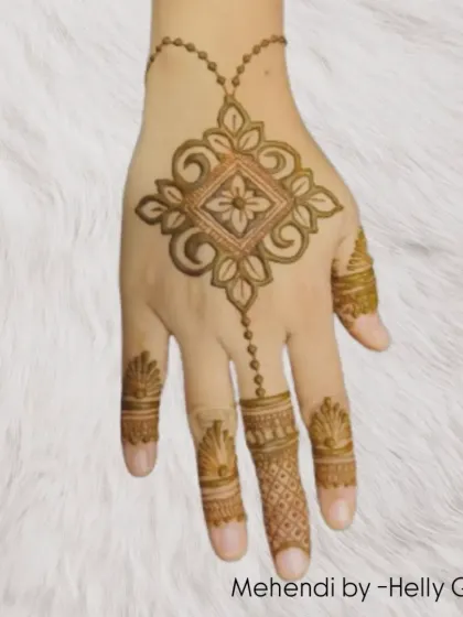 This design features a central geometric motif connected by a delicate chain to the finger. It's a modern, jewelry-inspired look that is both elegant and minimalist.