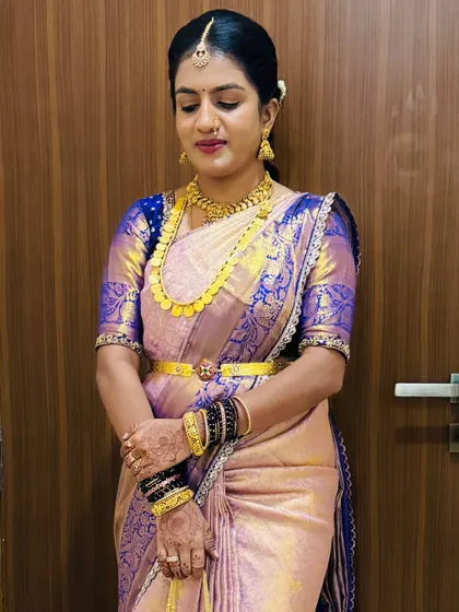 A beautiful client in a lavender and blue silk saree. The makeup is soft and enhances her features, paired with traditional gold jewellery.