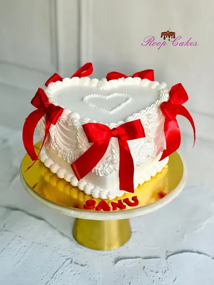 Elegance in simplicity. This vintage-style heart-shaped cake is adorned with delicate piping and beautiful red ribbons.