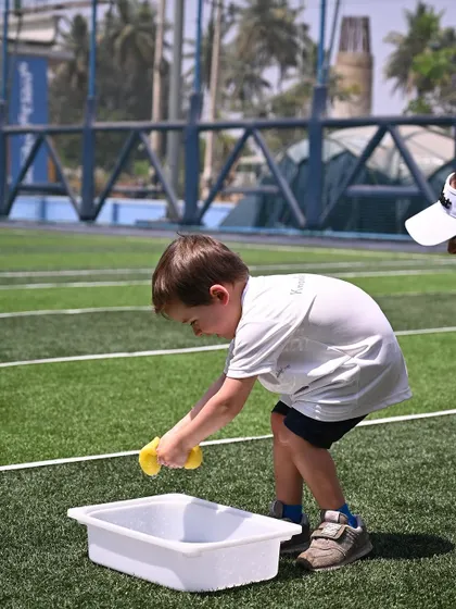 Another young athlete participates in the sponge-squeezing race. Our sports day activities are designed to be age-appropriate, ensuring everyone can participate and feel successful.